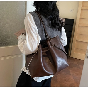 Detail of dark brown leather tote bag with unique knotted handle and natural texture