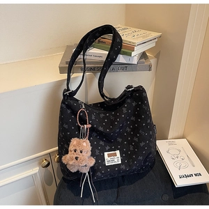 Detail of black canvas tote bag with heart patterns and a brown plush bear keychain