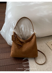 Detail of a brown suede Hobo bag with gold hardware and removable shoulder strap