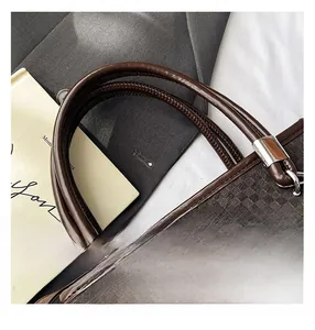 Detailed close-up of brown checkered handbag showing leather handles and metal hardware