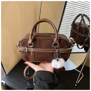 Detail of brown suede Boston bag featuring smooth leather trim and white faux fur charm