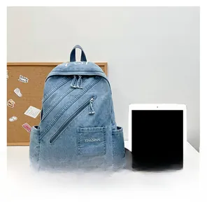 Blue denim backpack detail showing multi-zipper pockets and size reference with a tablet