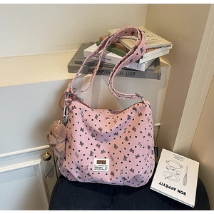 Detail of pink corduroy tote bag with heart patterns and a brown plush bear keychain