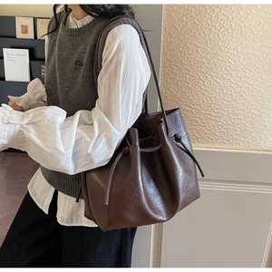 Detail view of large dark brown leather tote bag with drawstring and long shoulder straps