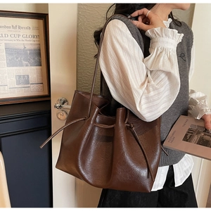 Detail of a deep brown tote bag with retro leather texture and drawstring sides for women
