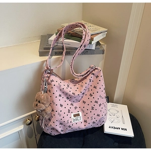 Pink corduroy tote bag detail with heart bow patterns and a plush bear pendant charm