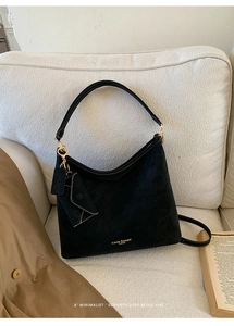Detail of black suede tote bag featuring white contrast stitching and gold hardware