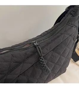 Macro detail of black quilted fabric with smooth metal zipper and woven pull cord