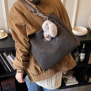 Detail of grey suede tote bag with chain strap and cute plush bunny charm accessory