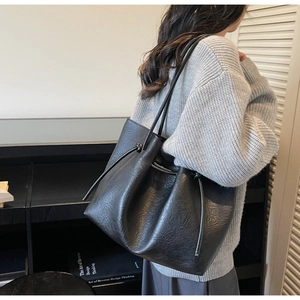 Detail of a large black leather tote bag with drawstring closure and soft texture