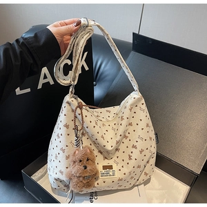 Detail of off-white corduroy tote bag with heart patterns and plush puppy charm