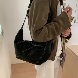 Détail du sac hobo noir avec surpiqûres blanches et bandoulière réglable sur modèle