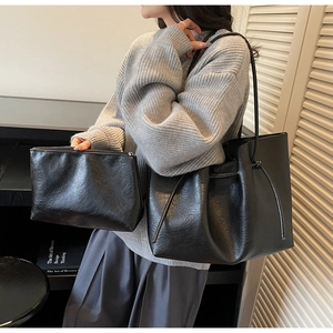 Detail of black faux leather tote bag set with matching zipper pouch and thin shoulder straps