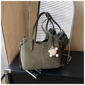 Close-up of deep olive green suede tote bag with drawstring details and plush pendant