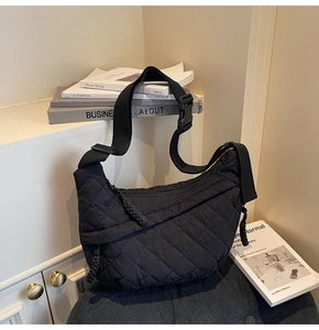 Close-up of black quilted dumpling bag with adjustable shoulder strap and woven zipper pull