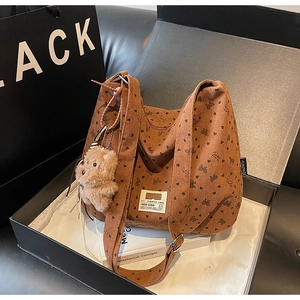 Close-up of caramel corduroy hobo bag with heart patterns and plush bear charm