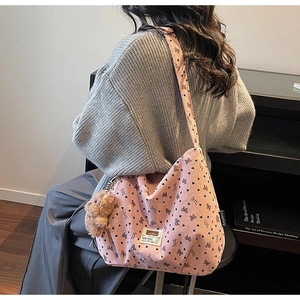 Détail du sac hobo en velours rose avec motifs de cœurs et pendentif ours en peluche