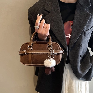 Close-up of vintage brown Boston bag with fuzzy ball and glove charm accessories