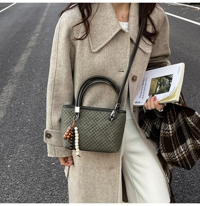 Close-up of checkered texture bucket bag with round handles and beaded tassel detail