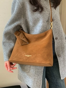 Brown suede tote bag with white stitching and mini pouch accessory on gray wool coat