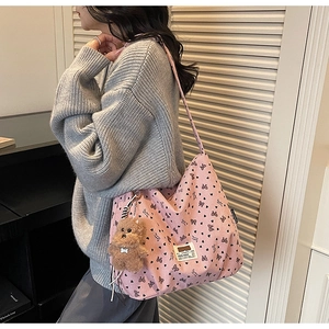 Close-up of pink corduroy tote bag with heart patterns and a brown plush bear charm