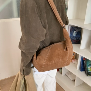 Détail d'un sac hobo en daim marron avec coutures blanches et bandoulière nouée