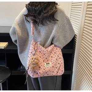 Detail of pink corduroy hobo bag with bow patterns and a brown plush puppy charm
