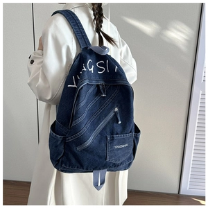 Detail of vintage navy denim backpack with white embroidery and side pocket feature