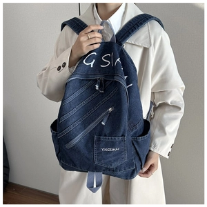 Detail shot of the multi-layered diagonal zippers and G Sl print on the denim backpack
