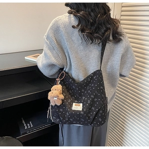 Close-up of black heart-patterned tote bag featuring a cute brown plush bear charm