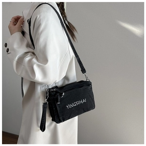Detail of the YINGSIHAI black denim crossbody bag shown on a beige trench coat