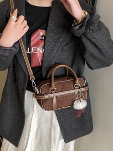Brown suede Boston bag with white stitching and decorative charms worn with a grey blazer