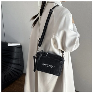 Detail of black denim crossbody bag with white letter print and silver metal buckles