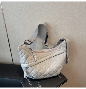Detail of grey quilted crescent bag with nylon strap and woven zipper puller