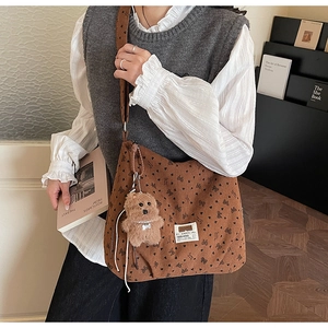 Detailed texture of brown corduroy tote bag with bow prints and a cute teddy charm