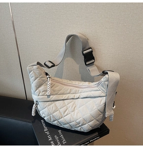 Detail of quilted rhombic pattern on lightweight crossbody crescent bag with strap