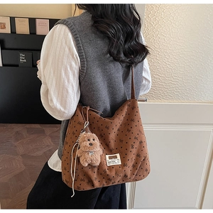 Detailed texture of brown corduroy hobo bag with bow prints and plush dog charm