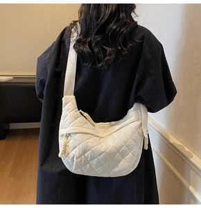 Rear view of a large white quilted crescent bag with diamond pattern and wide strap