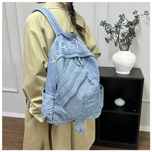 Close-up of blue denim backpack showing multi-zipper pockets and durable textile texture