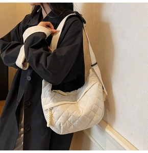 Detail of quilted diamond pattern on large cream crossbody bag with braided zipper puller