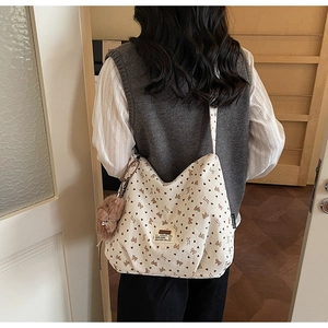 Detail of white corduroy tote bag with heart patterns and brown plush bear charm