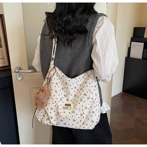 Rear view of a beige corduroy tote bag with floral bear patterns and a teddy bear charm