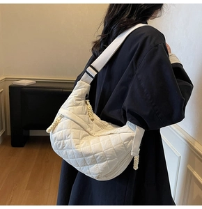 Side view of model wearing a white quilted dumpling bag with adjustable strap
