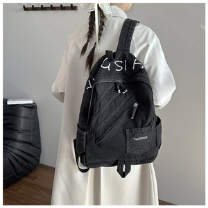 Detail of black denim backpack showing industrial zip accents and the GSIA letter print