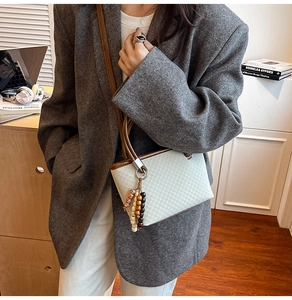 Detail of white checkered mini bucket bag with brown leather handles and wooden beads