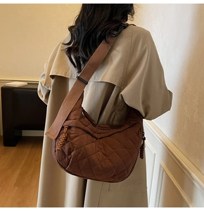 Detail of dark brown quilted crossbody bag with adjustable wide strap on trench coat