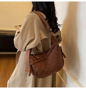 Detail of dark brown quilted crossbody bag shown from a side-back view on model