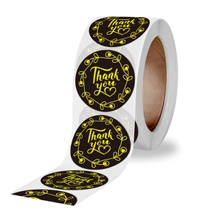 Roll of round black Thank You stickers with gold lettering and decorative floral wreaths