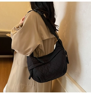 Close-up of black quilted dumpling bag worn with a khaki coat for a stylish look