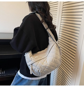 Quilted off-white crossbody crescent bag with wide canvas strap shown on model's back